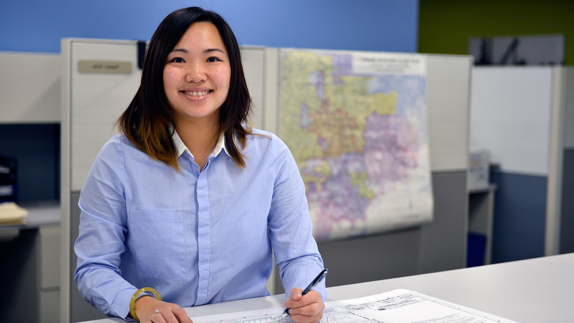 Woman working at a drafting table in front of a map